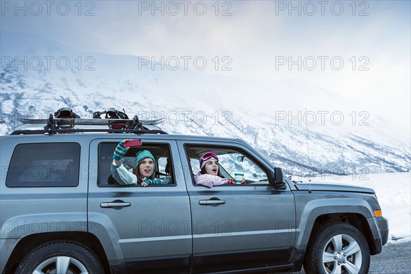 Friends photographing from car in winter