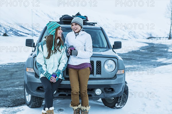 Caucasian women laughing near car in winter