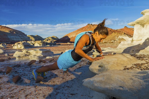 Native American woman doing push-up on rock in desert