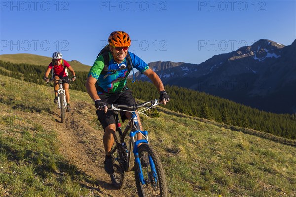 Caucasian couple mountain biking on trail