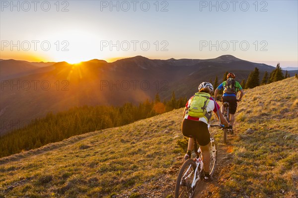 Caucasian couple mountain biking on trail