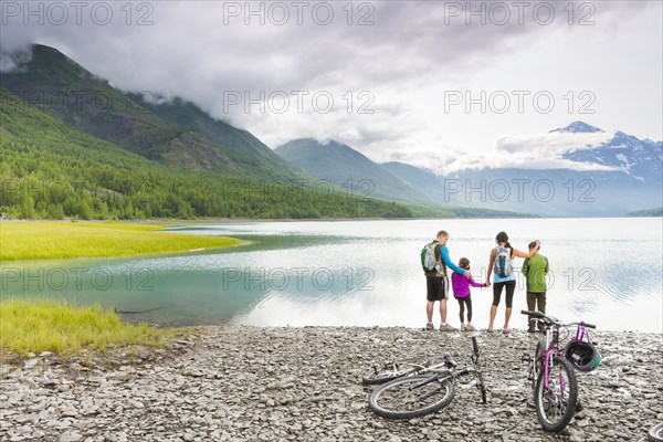 Couple with son and daughter riding bicycles near lake