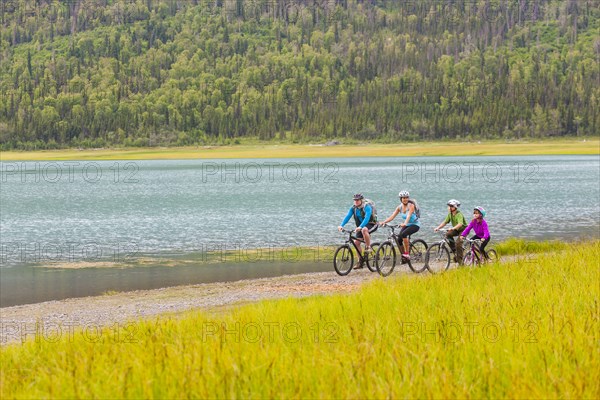 Couple with son and daughter riding bicycles near lake