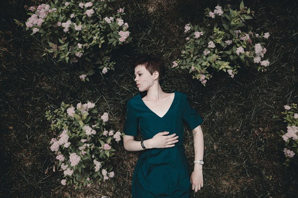 Caucasian woman laying in grass near flowers