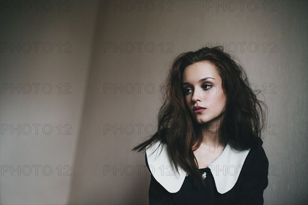 Portrait of Caucasian woman with messy hair near wall