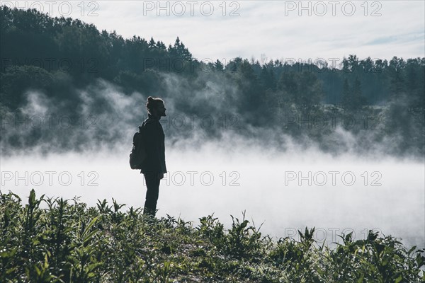 Caucasian man carrying backpack in foggy landscape