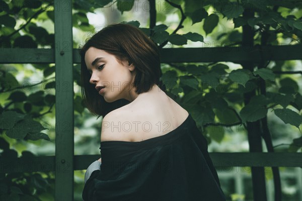 Caucasian woman baring shoulder near foliage