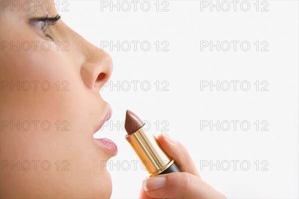 Mixed race woman applying lipstick