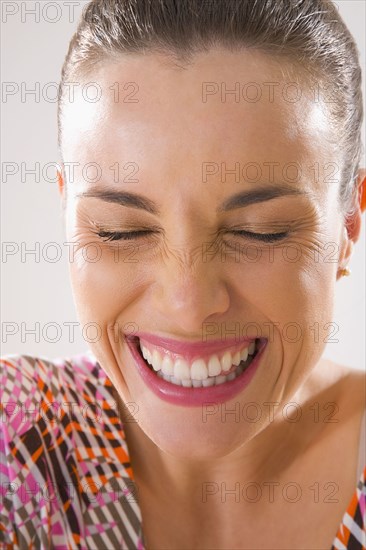 Mixed race woman smiling and grimacing with eyes closed