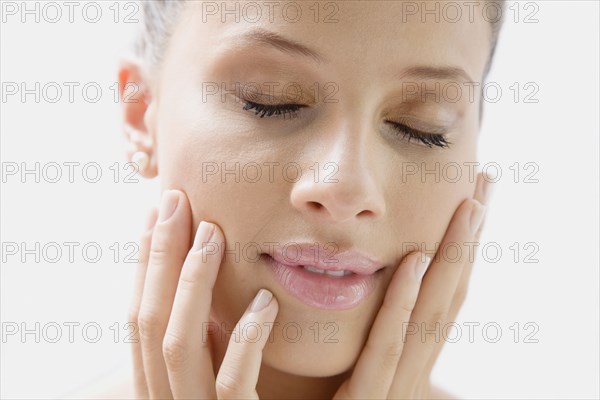 Mixed race woman with head in hands and eyes closed