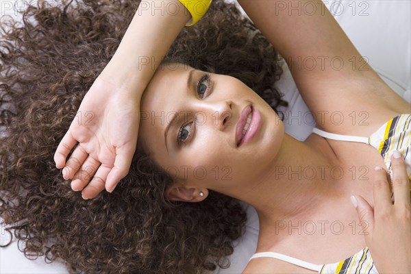 Mixed race woman laying with arm over forehead