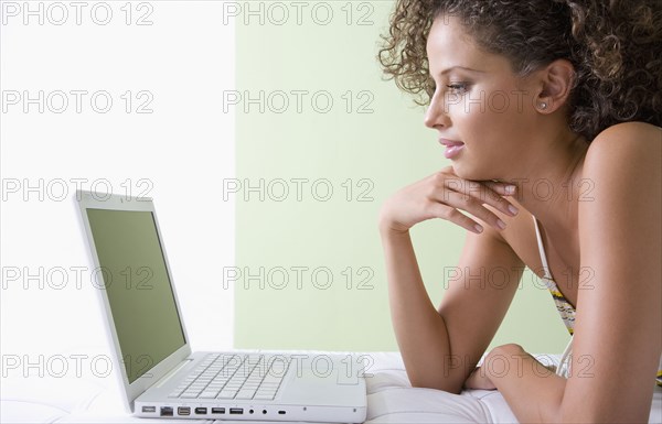 Mixed race woman laying on sofa using laptop