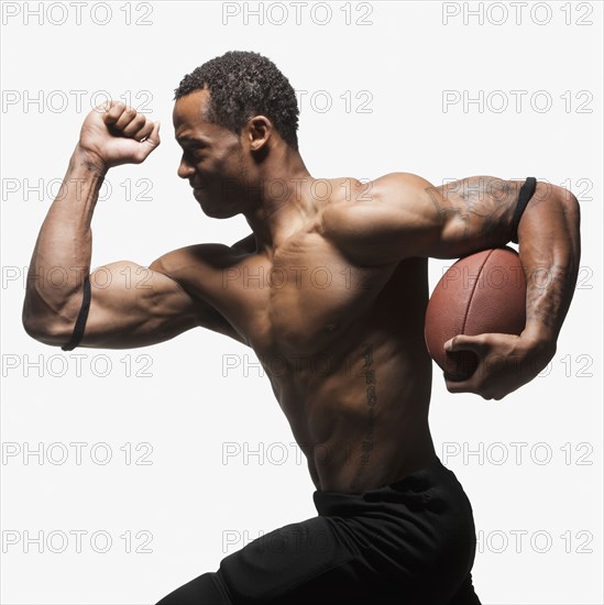 Bare chested football player running with football