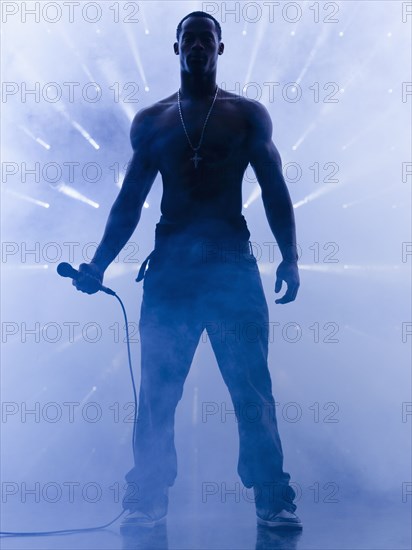 Back lit African singer holding microphone