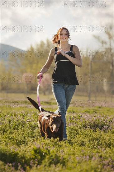 Caucasian woman running in field with dog