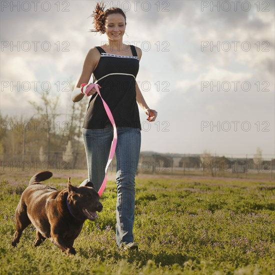 Caucasian woman running in field with dog