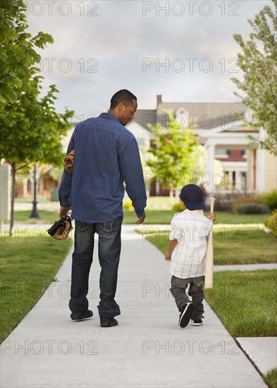 Father and son walking with baseball glove and bat