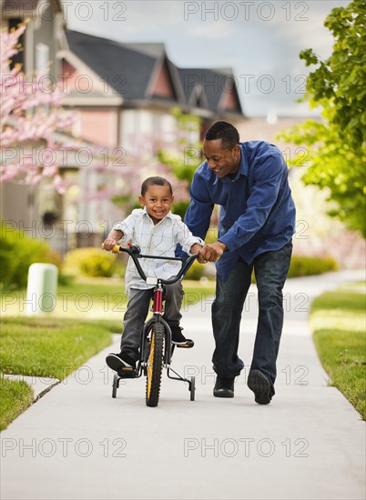 Father teaching son to ride bicycle