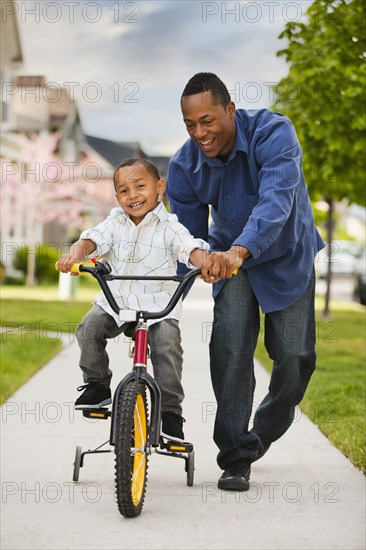 Father teaching son to ride bicycle