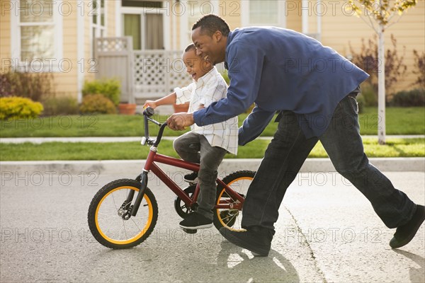 Father teaching son to ride bicycle