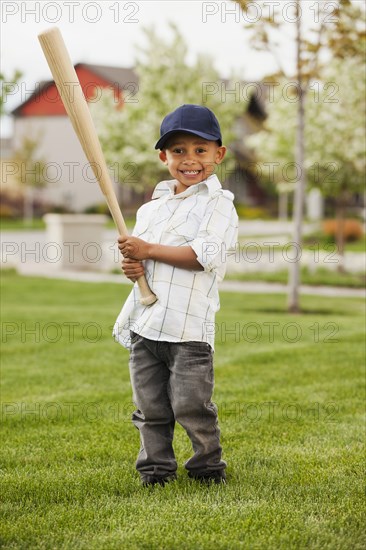 Mixed race boy playing baseball in grass