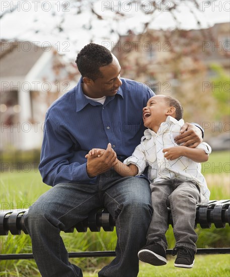 Father and son sitting together on park bench