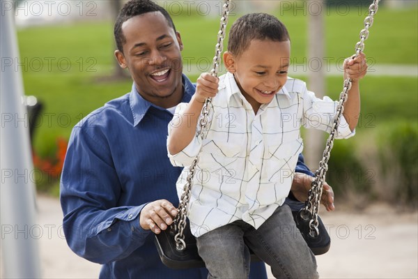 Father pushing son on swing