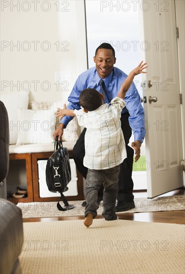 Businessman returning from work being greeted by son
