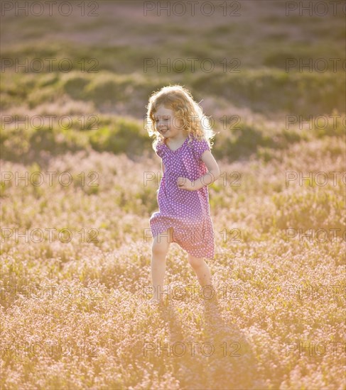 Caucasian girl running through field of flowers