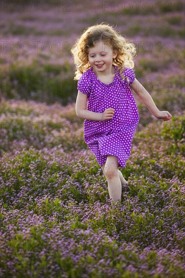 Caucasian girl running through field of flowers