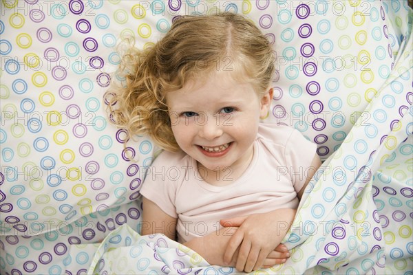 Smiling Caucasian girl laying in bed