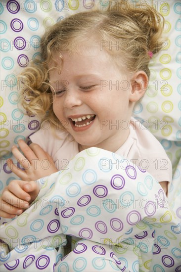 Grinning Caucasian girl laying in bed