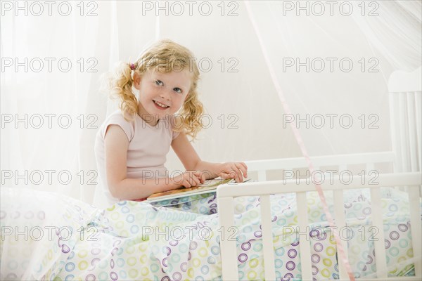 Caucasian girl reading in bed