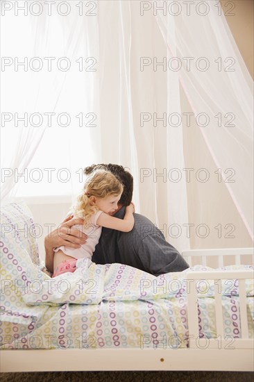 Caucasian father hugging daughter in bed