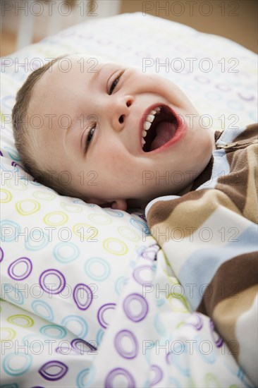 Laughing Caucasian boy laying in bed