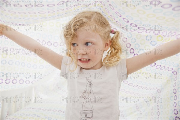 Caucasian girl playing underneath bed sheet