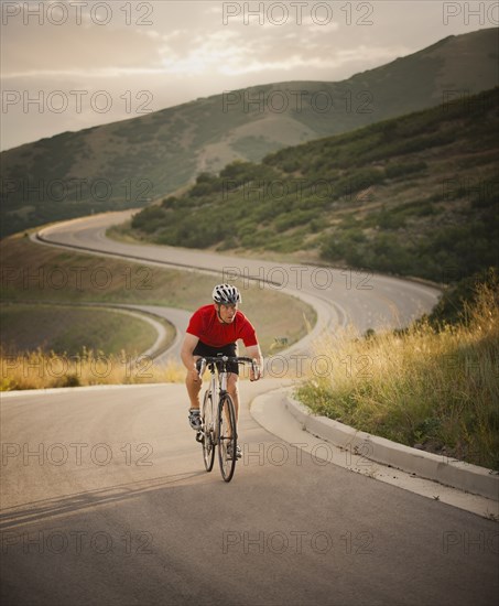 Caucasian man riding bicycle on remote road