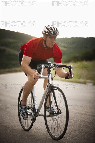 Caucasian man riding bicycle on remote road