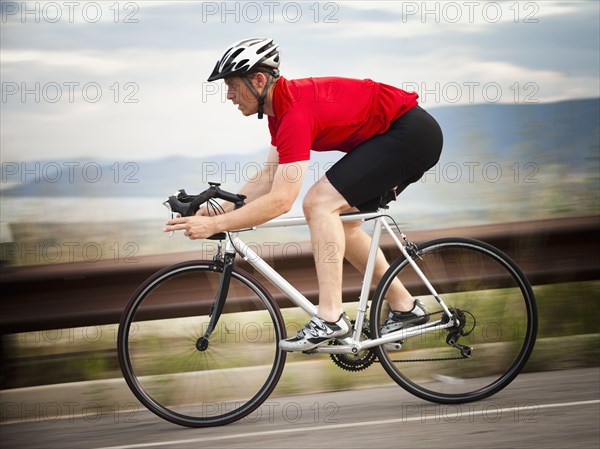 Caucasian man riding bicycle on remote road