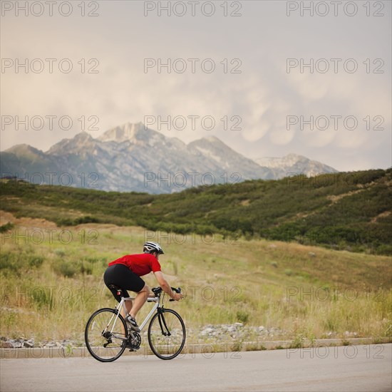 Caucasian man riding bicycle on remote road