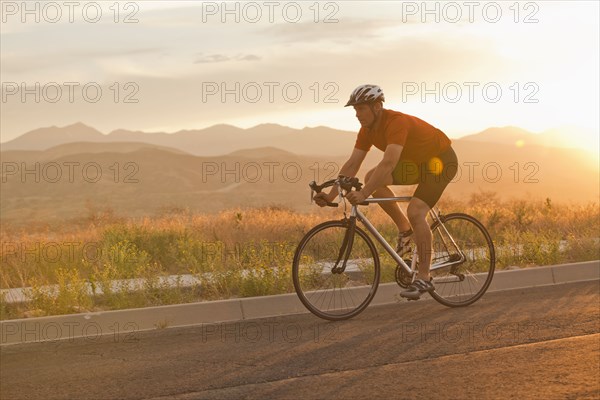 Caucasian man riding bicycle on remote road