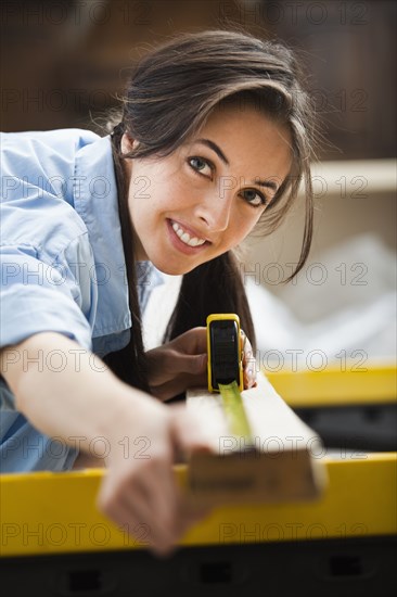 Caucasian woman measuring wood