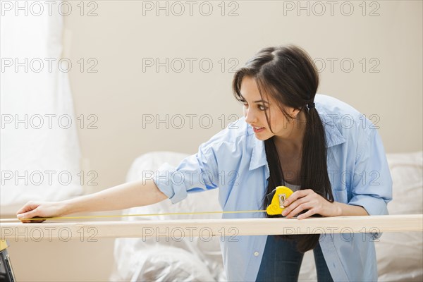 Caucasian woman measuring wood