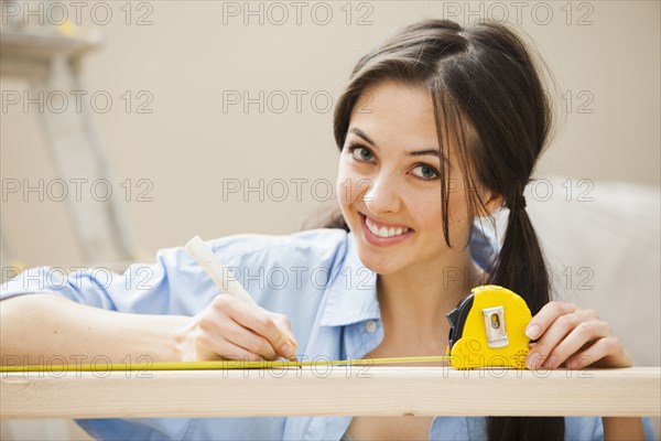 Caucasian woman measuring wood