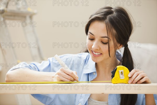 Caucasian woman measuring wood