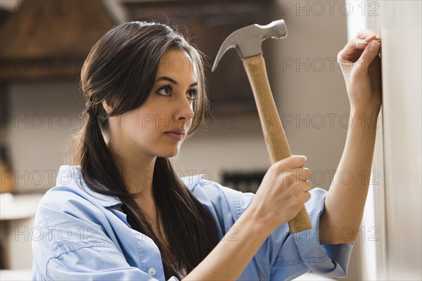 Caucasian woman hammering nail into wall