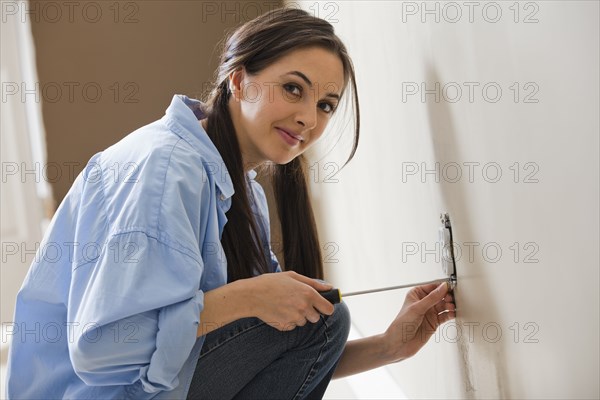 Caucasian woman working on electrical outlet