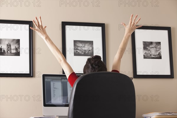 Caucasian woman cheering at desk in home office