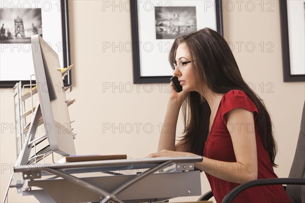 Caucasian woman talking on phone at desk in home office