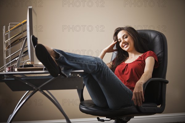 Caucasian woman with feet up on home office desk